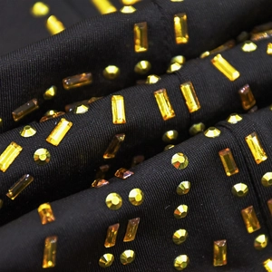 Detail shot of golden rectangular and round rhinestones on black elastic fabric