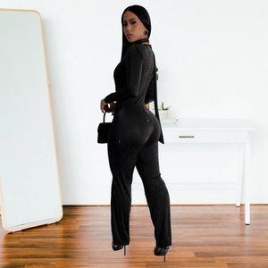 Detail of sparkling rhinestone embellishments on the black long-sleeve jumpsuit fabric