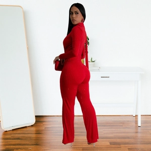 Close-up of sparkling rhinestone embellishments on a red long sleeve V-neck jumpsuit