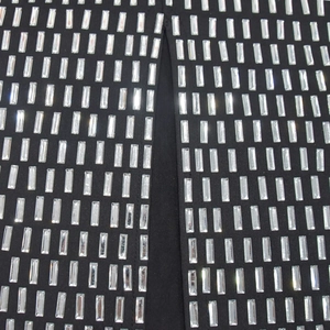 Macro detail of rectangle crystal rhinestones on black fabric for elegant long dress