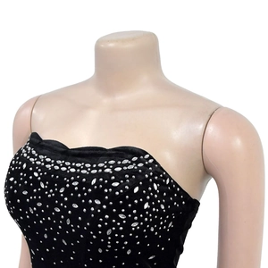Détail d'une robe en velours noir à épaules dénudées avec des strass argentés dégradés