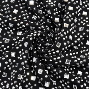 Dettaglio macro del tessuto nero dell'abito con strass geometrici scintillanti