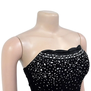 Détail d'une robe en velours noir à épaules dénudées avec des strass argentés brillants