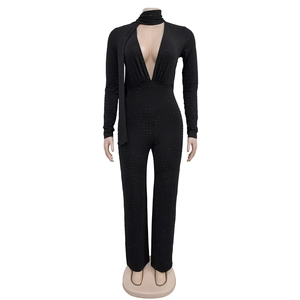 Detail of black long sleeve jumpsuit featuring deep V-neck and sparkling rhinestone accents