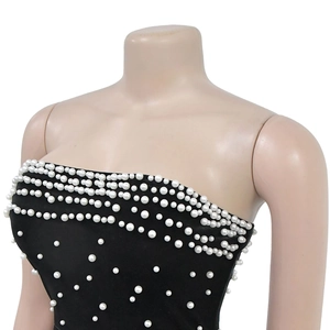 Détail de l'embellissement de perles blanches sur un corsage noir de robe bustier de soirée