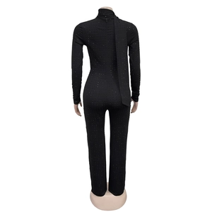 Macro detail of black sequined jumpsuit with long sleeves and elegant neck ribbon