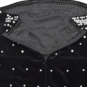 Détail d'une robe en velours noir avec perles et clous montrant une fermeture éclair invisible