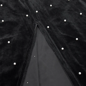 Détail de l'ourlet de la robe en velours avec fente et élégantes perles blanches brodées