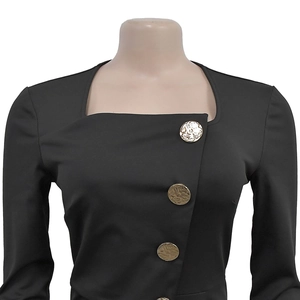 Detail of vintage gold embossed buttons on a sleek black long-sleeve jumpsuit