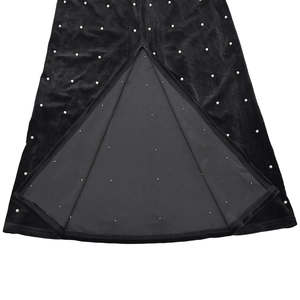 Détail de l'ourlet d'une robe en velours noir avec perles et fente élégante