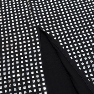 Détail des strass carrés sur tissu noir avec une finition fendue élégante sur la robe