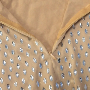 Gros plan détaillé de la fermeture éclair invisible et des strass sur la robe beige