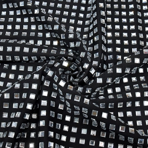 Détail macro du tissu noir de la robe avec des strass argentés étincelants en grille