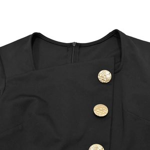Detail of square neckline with hidden zipper and textured gold buttons on black jumpsuit