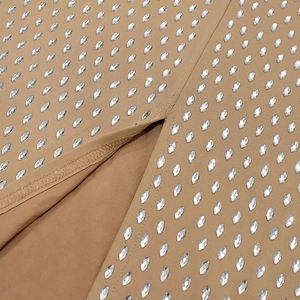 Détail macro d'une robe moulante kaki avec ornements en strass et coutures de qualité