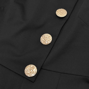 Detail of three vintage gold hammered buttons on a sleek black long-sleeved jumpsuit