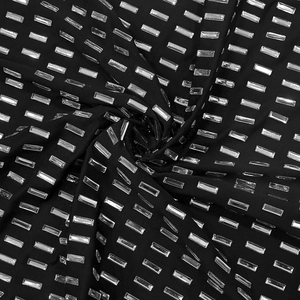 Vue détaillée de strass rectangulaires argentés sur le tissu noir extensible de la robe