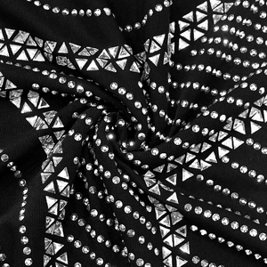 Détail du tissu noir avec des strass brillants et des clous géométriques argentés