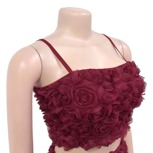 Dettaglio del crop top bordeaux con rosette floreali 3D e spalline sottili