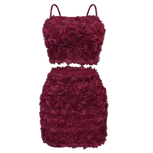 Dettaglio di applicazioni di rose 3D su un completo due pezzi bordeaux con top e gonna