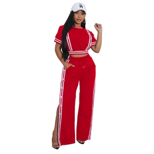 Dettaglio del set rosso con crop top e pantaloni con strisce bianche laterali e bottoni a pressione
