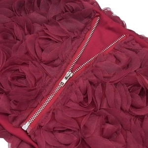 Dettaglio di un completo bordeaux con tessuto a rose 3D e cerniera in metallo argentato