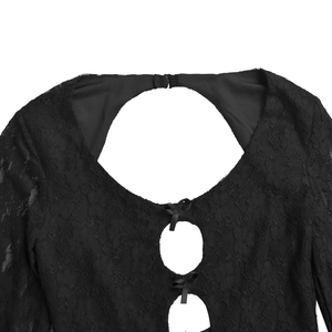 Détail de la dentelle florale noire avec découpes ajourées et nœuds en ruban de soie