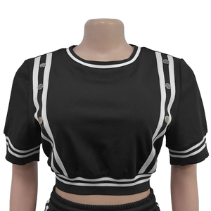 Dettaglio del crop top nero con strisce bianche laterali e fibbie metalliche sulle spalle