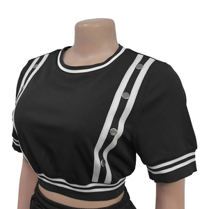 Dettaglio del crop top a maniche corte con bordo a righe bianche e nere e bottoni argento