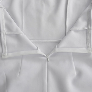 Close-up of invisible zipper and overlock stitching on a white off-shoulder mini dress