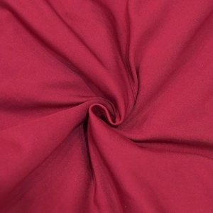 Dettaglio del tessuto a maglia rosso vino con sottili strisce verticali e drappeggio
