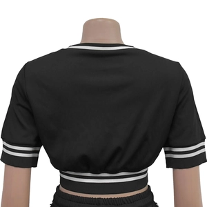 Dettaglio del crop top nero a maniche corte con strisce bianche sull'orlo inferiore
