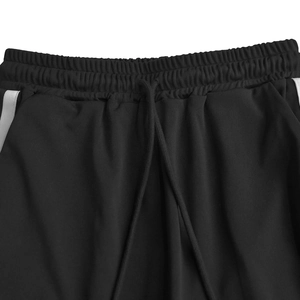 Dettaglio dell'elastico in vita con cordoncino e striscia laterale sui pantaloni neri