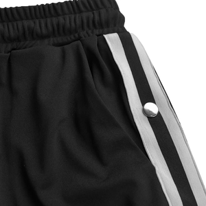 Dettaglio ravvicinato dei pantaloni neri con elastico in vita e bottoni a pressione