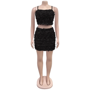 Dettaglio di crop top e minigonna in tessuto nero con petali di fiori 3D in rilievo