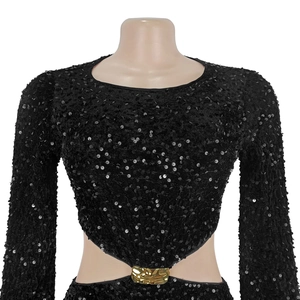 Détail d'une robe noire à paillettes avec découpe à la taille et boucle en métal doré