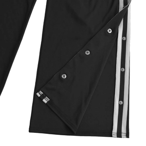 Dettaglio dei pantaloni sportivi con strisce bianche laterali e bottoni a pressione in metallo
