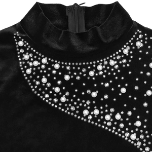 Détail d'une robe en velours noir avec perles, strass et fermeture éclair à l'arrière