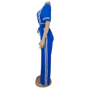 Dettaglio laterale della tuta blu reale con pantaloni a gamba larga e bottoni a pressione