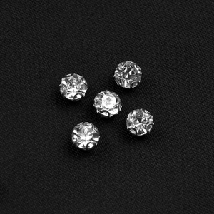 Gros plan de strass sertis en argent sur le tissu noir texturé de la robe de soirée