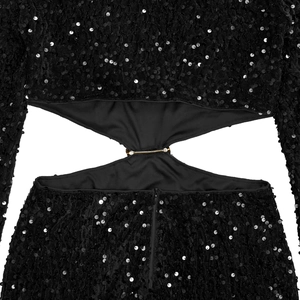 Détail de robe noire à paillettes avec découpe à la taille et boucle en métal doré