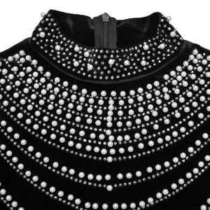 Dettaglio dell'abito in velluto nero a collo alto con perle e strass decorativi