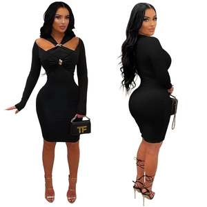 Détail d'une robe moulante noire à manches longues avec décolleté ajouré et boucle dorée chic