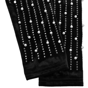 Dettaglio della manica in velluto nero con strass scintillanti e perle bianche