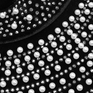 Dettaglio di perle bianche e strass scintillanti sul tessuto in velluto nero