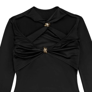 Détail du haut noir à manches longues avec découpes croisées et boucles dorées
