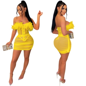Dettaglio dell'abito in rete giallo con piume e struttura a corsetto con arricciature