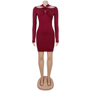 Détail d'une robe moulante bordeaux avec épaules dénudées et boucle métallique décorative
