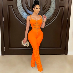 Detail of bright orange two-piece set featuring mesh bustier top and high waist zipper pants