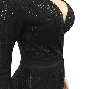 Dettaglio dell'abito nero con paillettes, scollo a V profondo e vita in raso